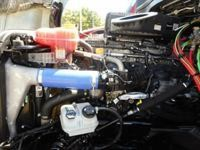 Engine bay of 2023 Freightliner Cascadia 126 shows coolant reservoir, hoses, and various engine components visible.