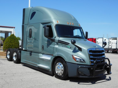 Tractor unit showing a Freightliner Cascadia 126 sleeper cab with chrome wheels and reinforced front bumper in a parking lot.