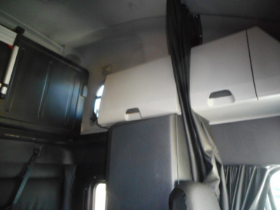 Interior cab area of a Freightliner Cascadia showing storage compartments and curtain, with seating and panels visible.