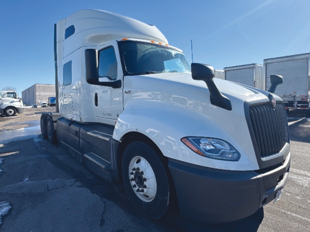 International LT625 sleeper cab tractor in white showing aerodynamic front with black grille, side mirrors, and cab steps.