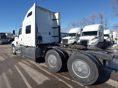 Truck cab and tandem rear axles of a 2023 International LT625 semi-truck seen in a lot with other trucks nearby.