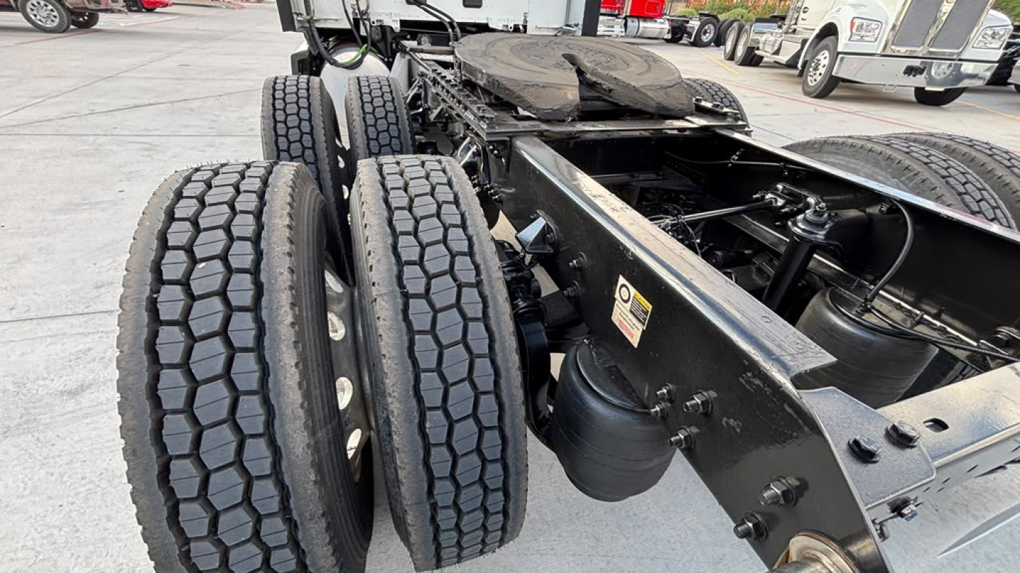 Kenworth truck chassis and rear axles showing dual rear axles and tires with fifth wheel area visible.
