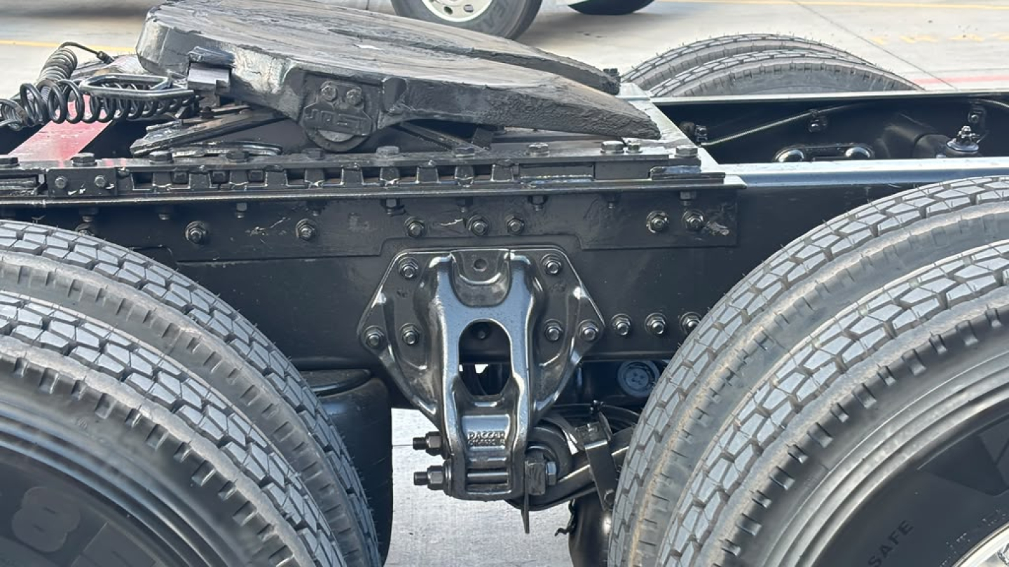 Kenworth T680 wheel and fifth wheel assembly close-up showing hitch and suspension components underframe.