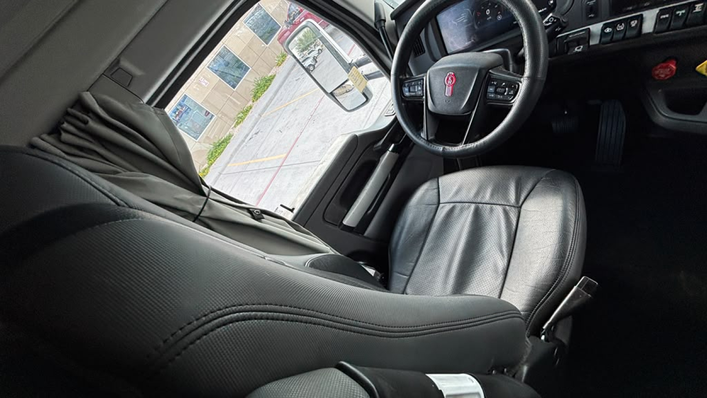 Kenworth T680 interior view showing dashboard steering wheel and driver seat in a sleeper cab.