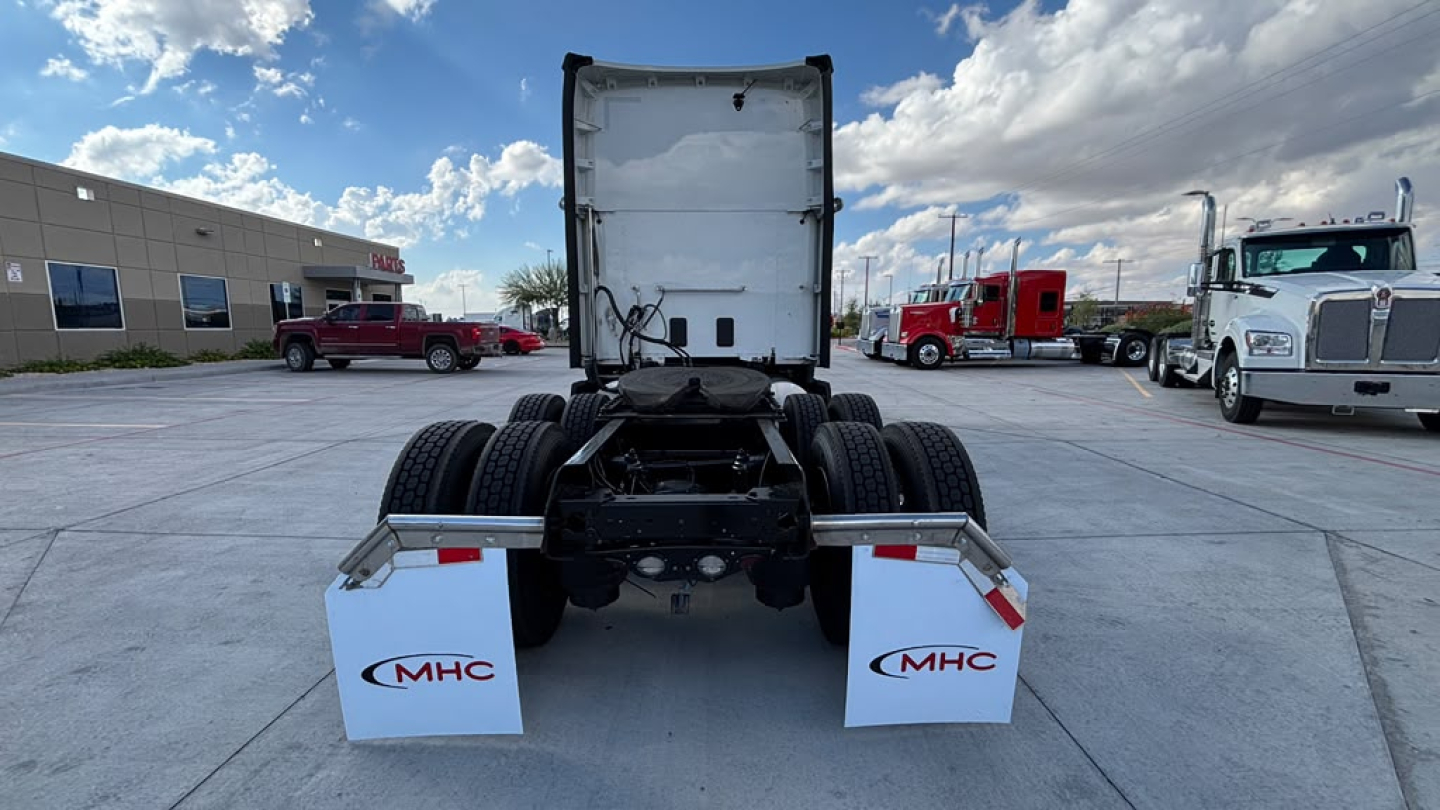 Kenworth T680 tractor rear view showing fifth wheel and dual rear tires with MHC mudflaps, in a dealership lot.