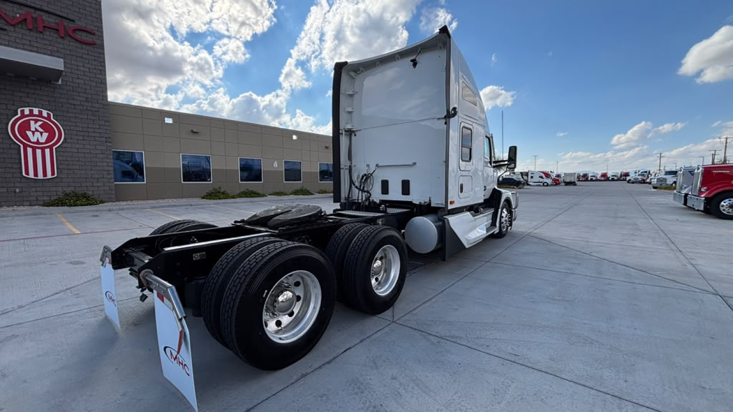 Kenworth T680 tractor rear view showing sleeper cab, dual rear axles, and fifth wheel in a dealership lot.