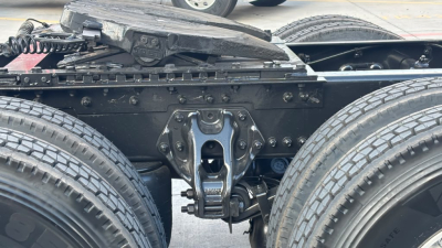 Kenworth T680 wheel and fifth wheel assembly close-up showing hitch and suspension components underframe.
