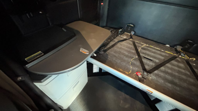 Kenworth truck interior showing sleeper cab area with storage chest and folded bunk, passenger seat area, and plastic desktop with a bed platform.