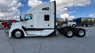 Kenworth T680 tractor side view showing sleeper cab with white paint and dual rear axles. Visible text not legible; features include windows, door, and fuel tanks.