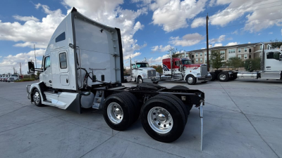 Kenworth T680 tractor trailer with sleeper cab, rear dual axle, side view showing chassis and fifth wheel, clear sky.
