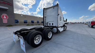 Kenworth T680 tractor rear view showing sleeper cab, dual rear axles, and fifth wheel in a dealership lot.