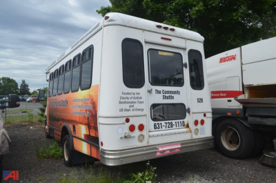 Ford E450 bus rear view showing decals, rear doors, taillights and license area.