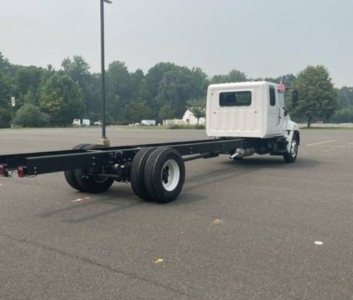 Truck cab chassis with long wheelbase frame and rear dual axle; white cab, black chassis, rear wheels visible.