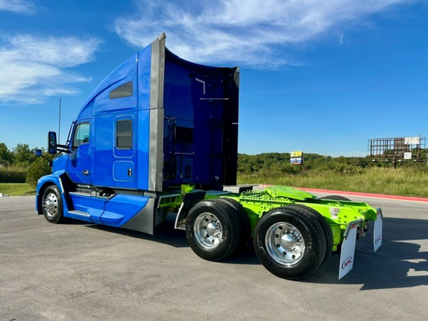 Kenworth T680 tractor unit, blue cab, sleeper, side view showing dual rear axles with green chassis and wheel covers.