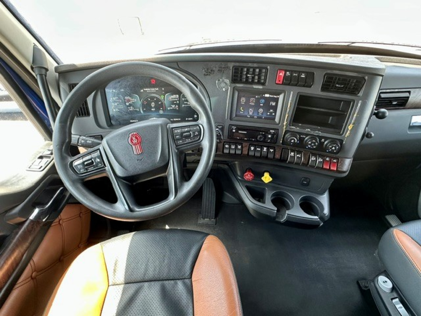 Kenworth T680 cab interior showing steering wheel, dashboard, and center console with controls and gauges.