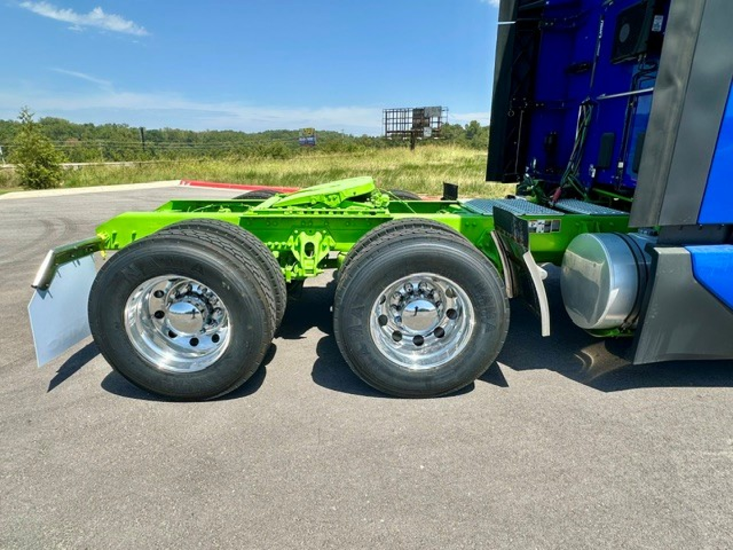 Kenworth T680 chassis showing dual rear axles and wheel rims, green frame with blue cab partial