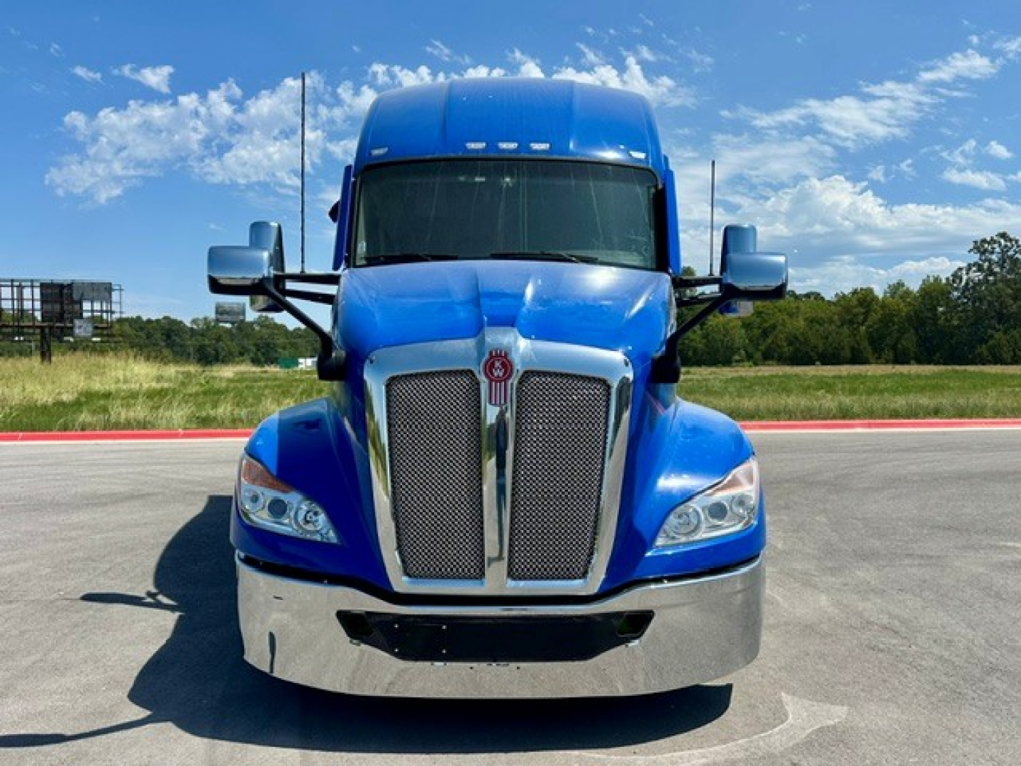 Kenworth T680 front view showing chrome grille, blue cab, and large bumper.