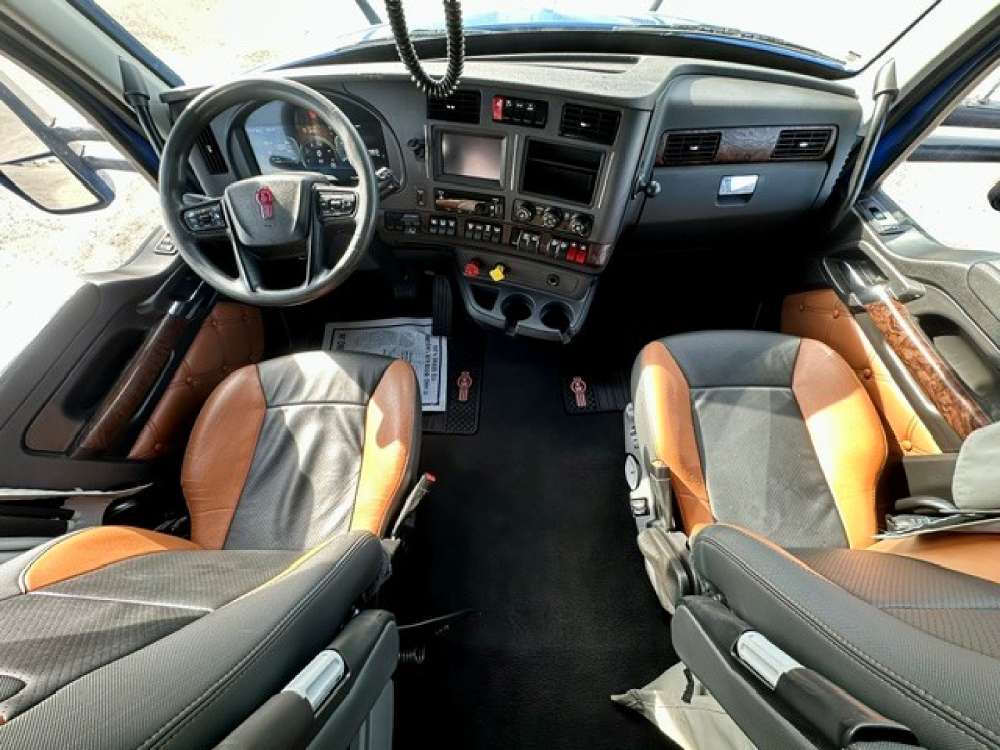 Kenworth T680 interior cab with dual seats, dashboard, steering wheel, and center console; visible controls and infotainment system.