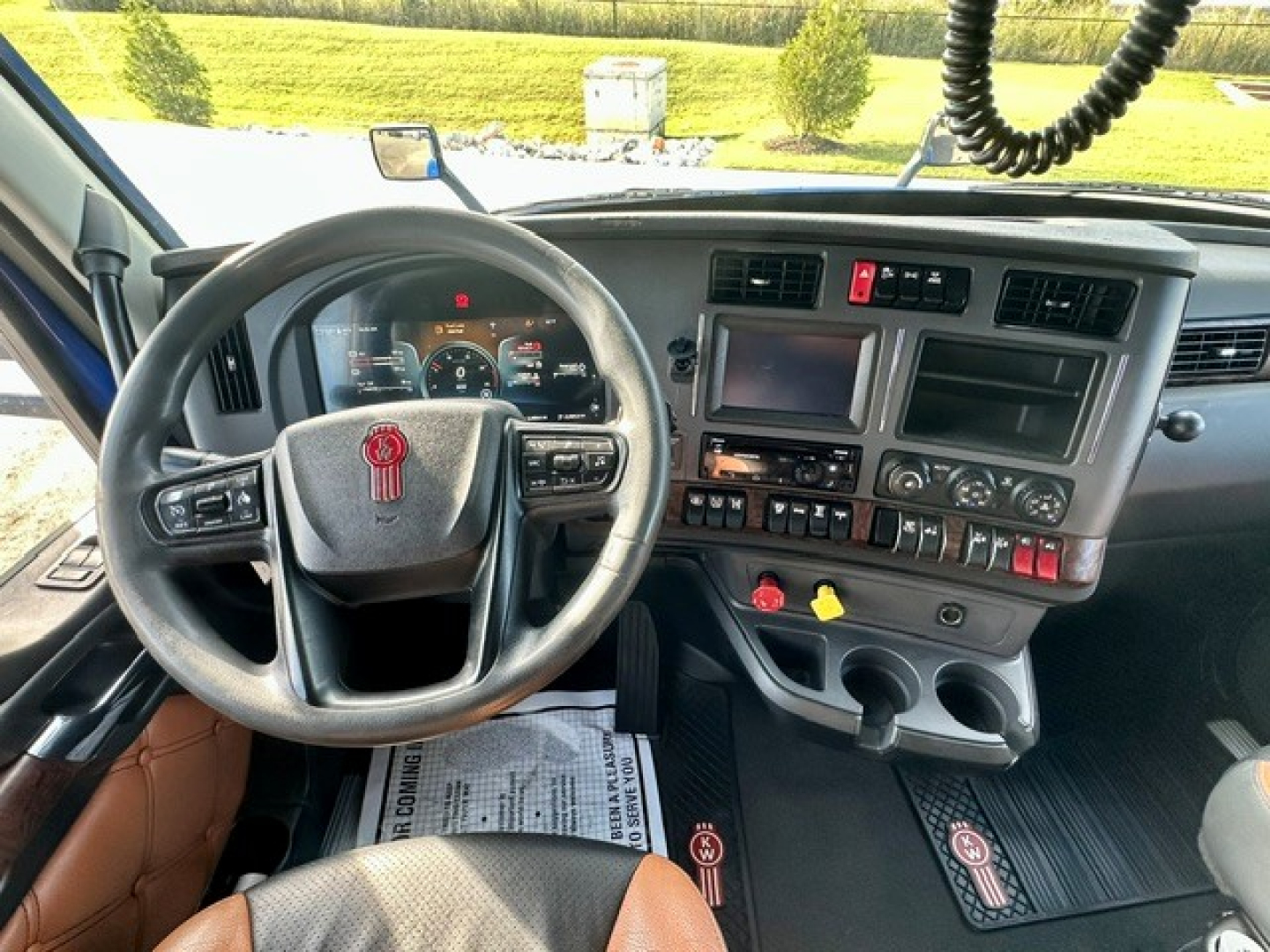 Kenworth T680 interior view showing steering wheel, dashboard, and center console with switches and gauges.
