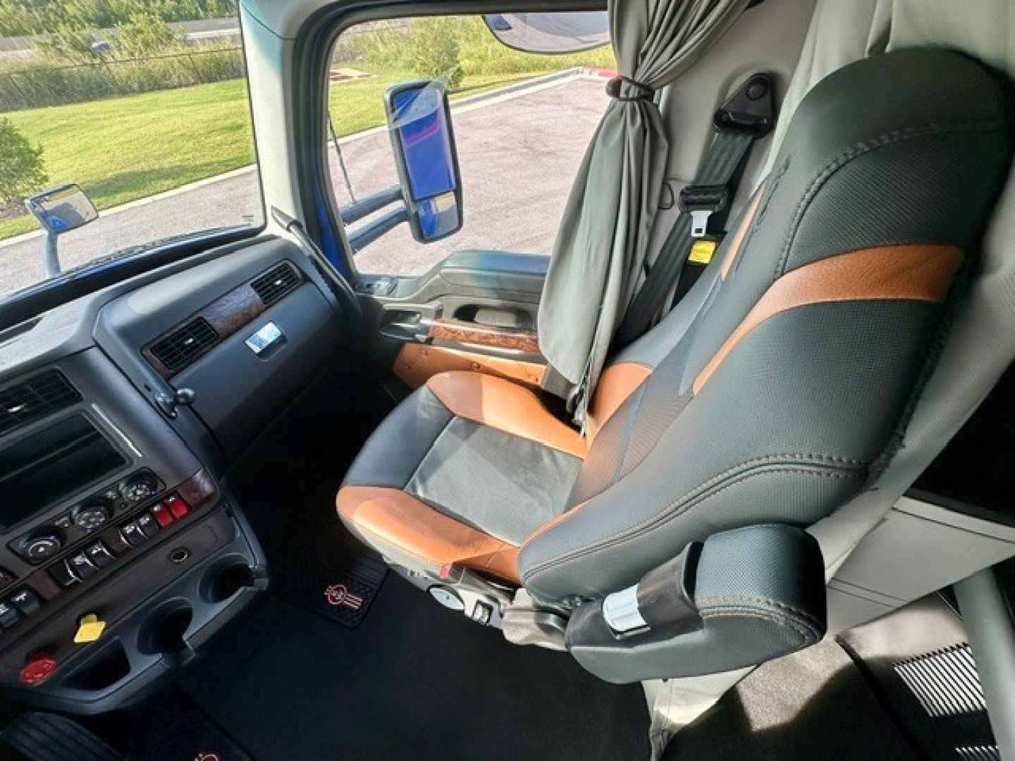 Kenworth T680 interior cabin seating and dashboard view showing driver seat and side window.