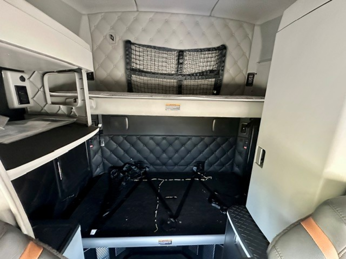 Kenworth T680 sleeper cab interior showing bunk bed area and storage shelves.