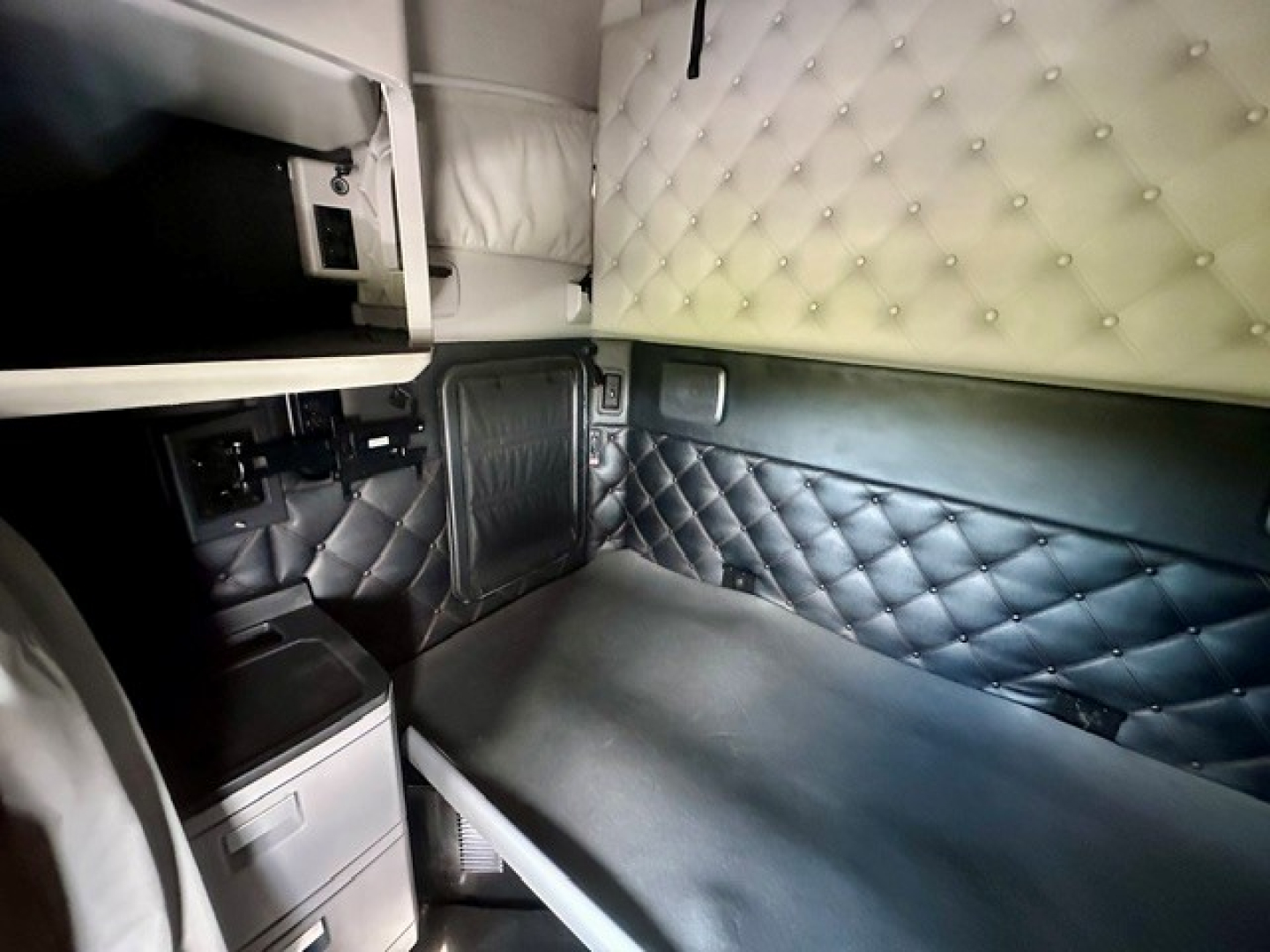 Kenworth T680 sleeper cab interior showing quilted white upper wall cushion and black lower side with storage compartments.