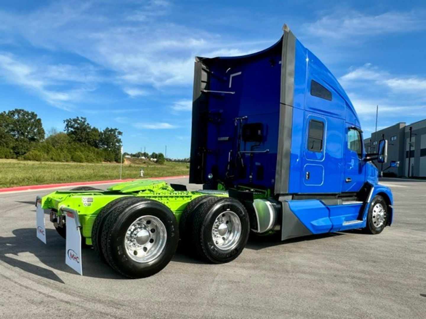 Kenworth T680 tractor in blue cab with green chassis, side view showing sleeper cab and dual rear axles.