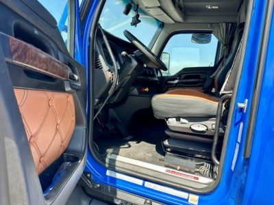Kenworth T680 cab interior view from doorway showing steering wheel, dashboard, and tan seat with brown trim.