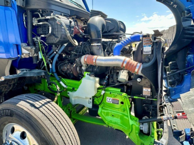 Kenworth T680 engine bay view showing green frame components and turbocharger piping.