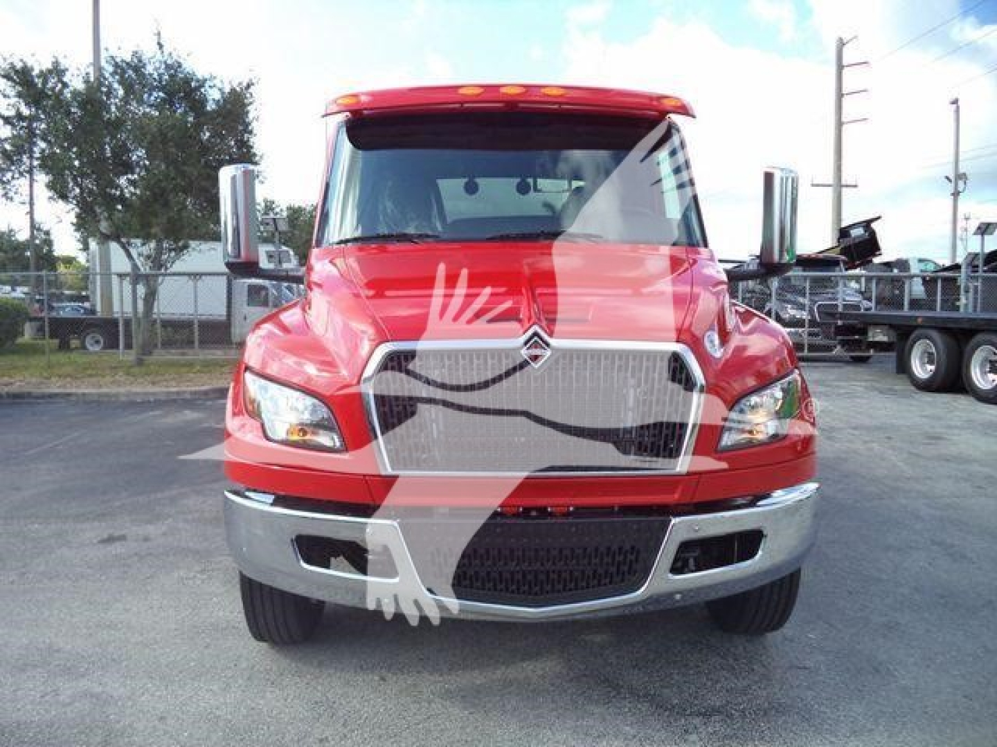 Red 2025 International MV front view showing grille, headlights, chrome bumper, and large windshield; winch category truck in dealership lot.