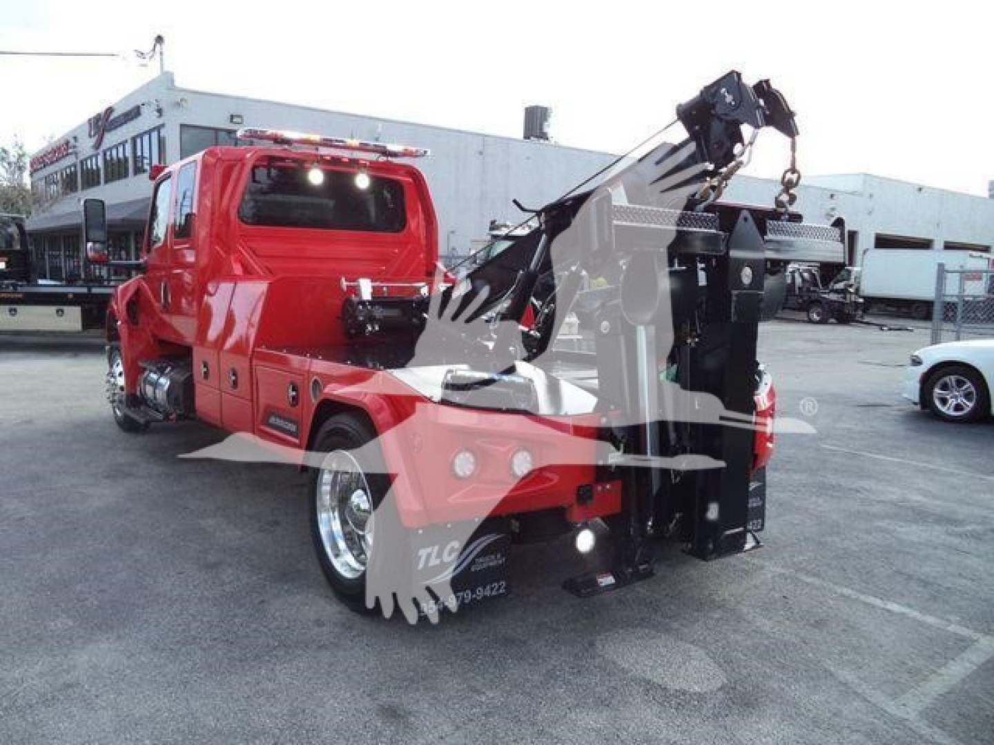Tow truck with crane/winch showing red cab and boom in service area