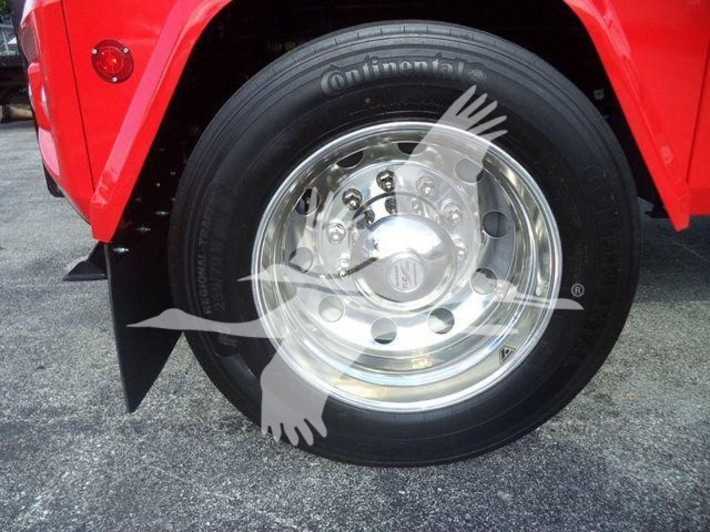 Truck wheel showing Continental tire and polished steel hubcap, red fender, black mudflap.