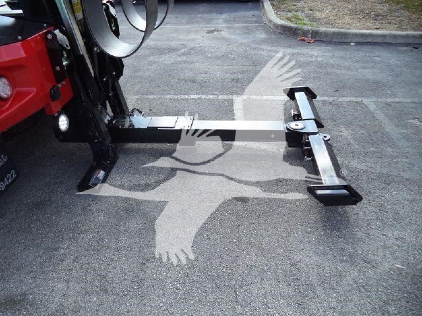 Winch-equipped truck hitch on a forklift-style loader showing a metal drawbar with black end hooks and a horizontal beam.
