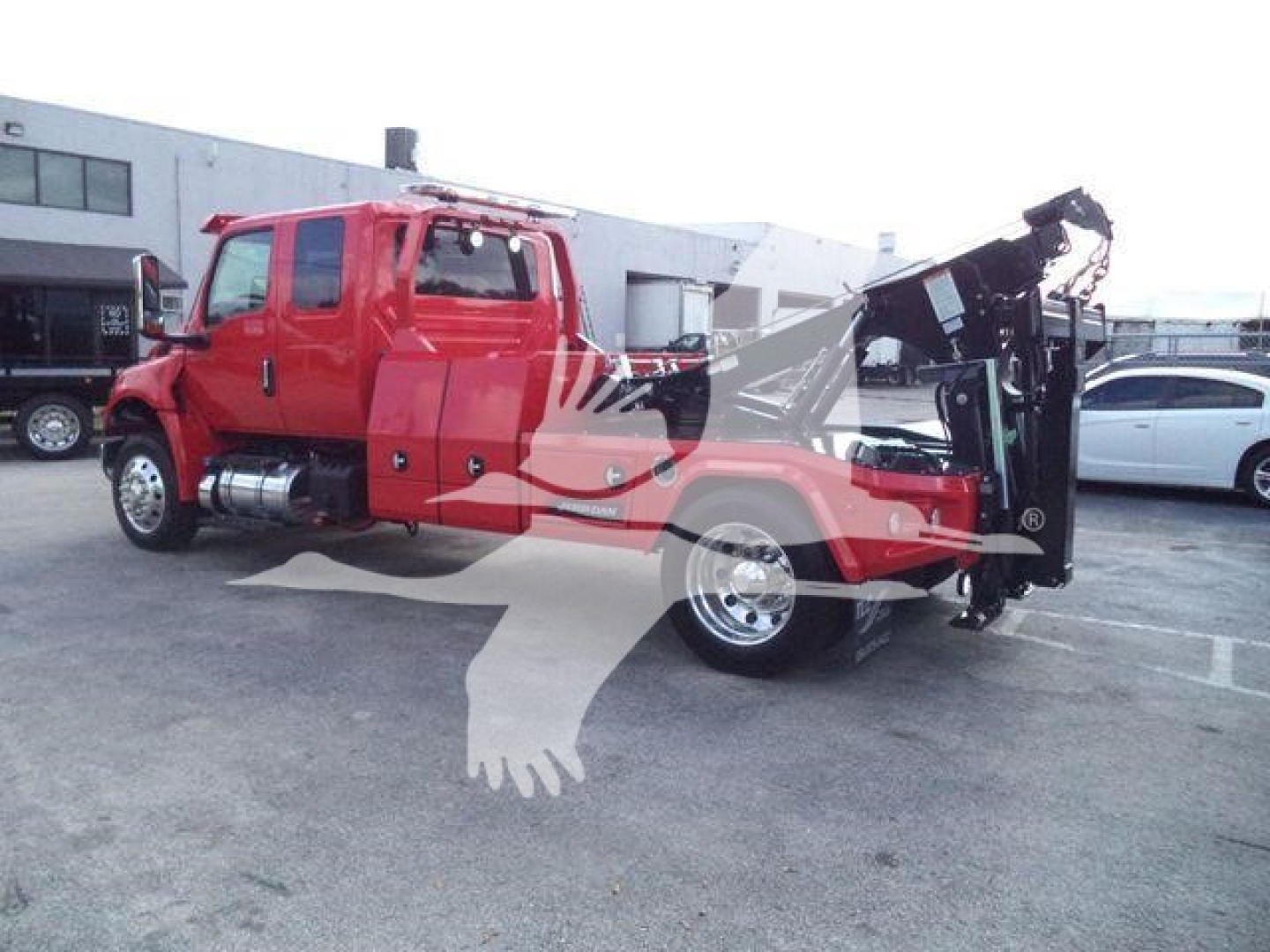 Tow truck with red cab and black hydraulic crane in rear, dual rear wheels, winch category vehicle, side view showing crane arm and boom
