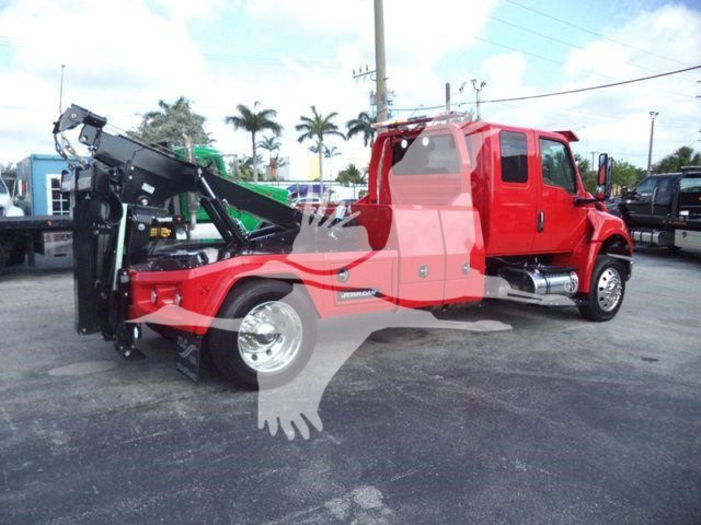 Truck with red cabin and black winch/loader attachment mounted at the front; International MV series truck for heavy recovery with hydraulic winch and crane-like arm folded.