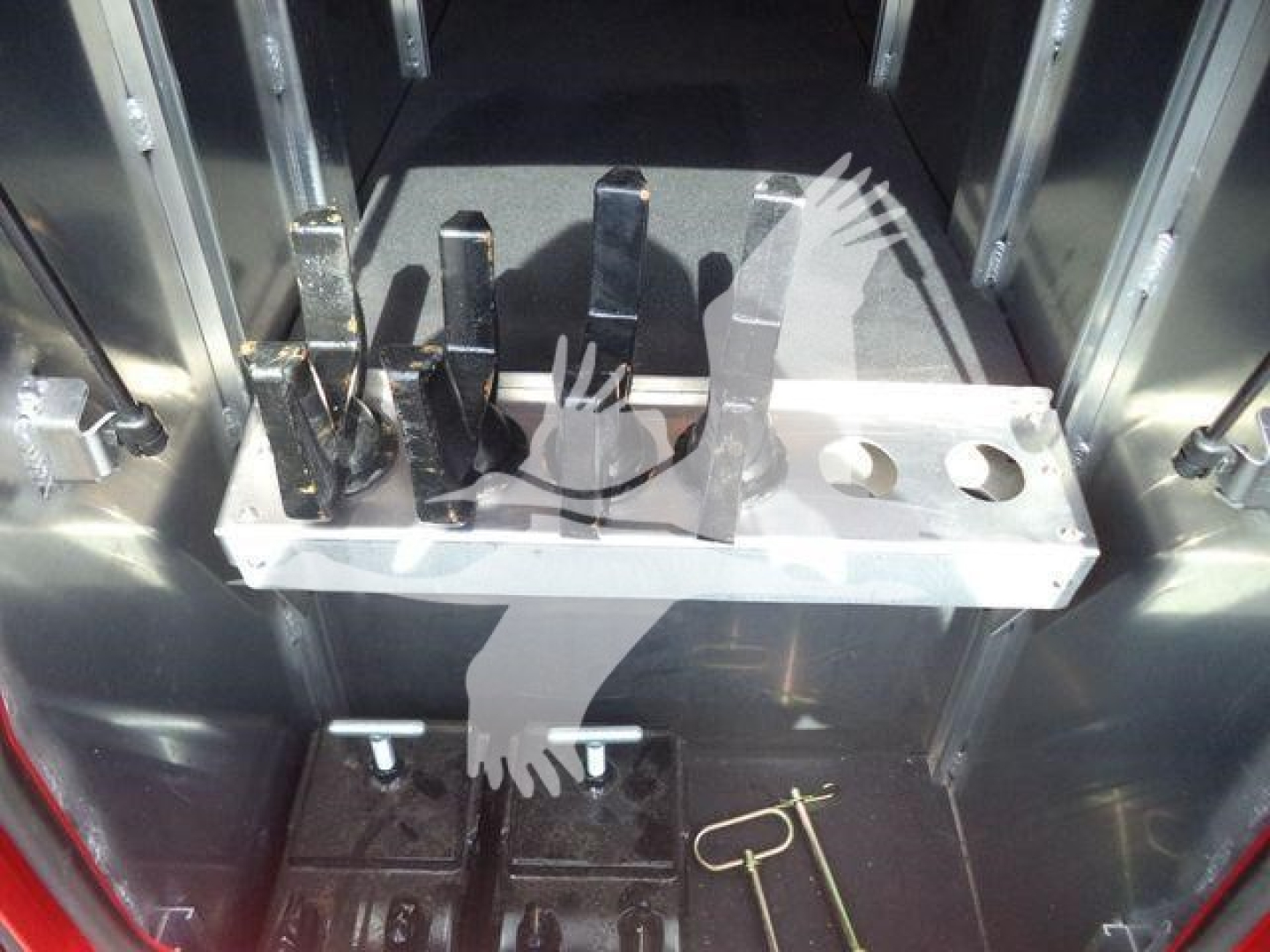 Metal tool tray with several black metal forks/pins in a cargo truck interior alongside a ring and pins. No visible text discernible on parts.