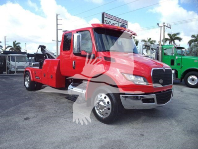 Front left side of a red 2025 International MV truck with extended cab and winch equipment, in a dealership lot.