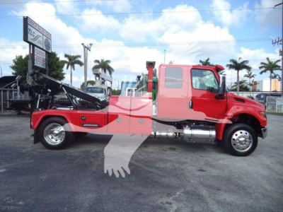 Truck side view showing a red International MV with a winch/rollover wreckers behind cab, stock number MPL60MVEXCABRED, glassy gravel lot.