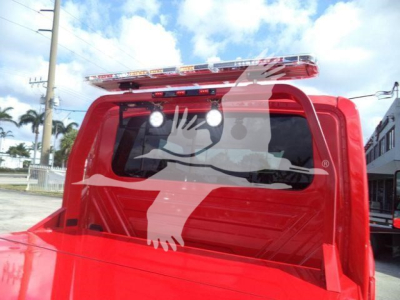 Truck cab rear window with white graphics and a red light bar on top.