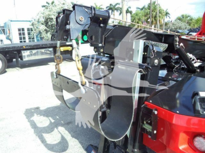 Winch assembly on truck chassis showing hydraulic winch mount and hook with chain, exposed hydraulic lines, and steel brackets.