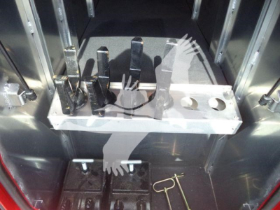 Metal tool tray with several black metal forks/pins in a cargo truck interior alongside a ring and pins. No visible text discernible on parts.