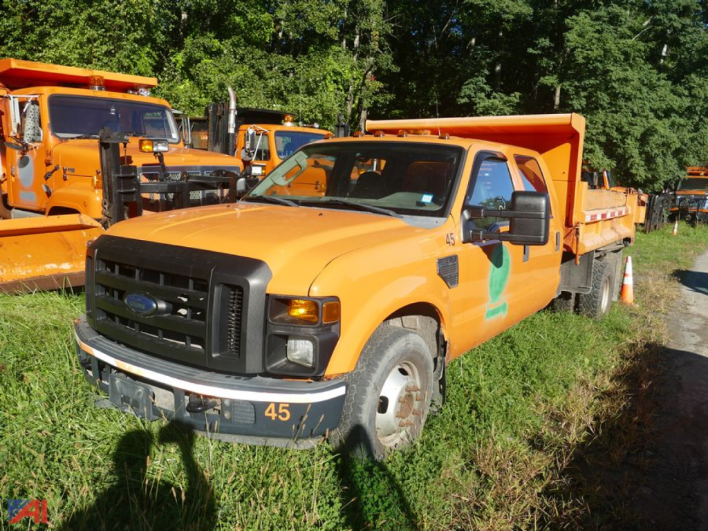 Ford F-350 Super Duty Cab and Chassis with dump bed showing dual rear wheels and orange color.