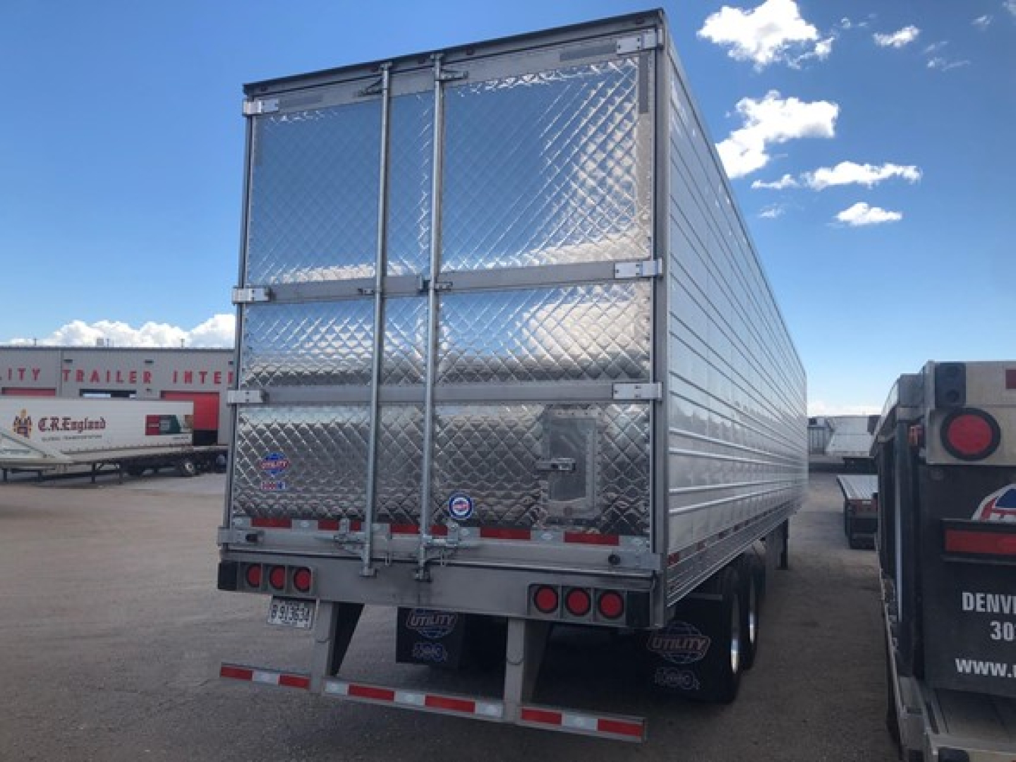 Rear/side view of a new 2026 Utility Utility 3000R refrigerated trailer with diamond plade aluminum walls, dual rear doors, and reflective safety stripes.