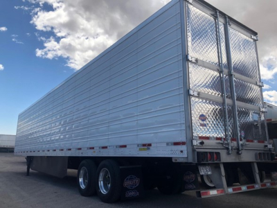 Tri-axle trailer with ribbed aluminum panels and diamond plate rear doors, reflective tape along sides, Utility 3000R reefers logo visible, side view