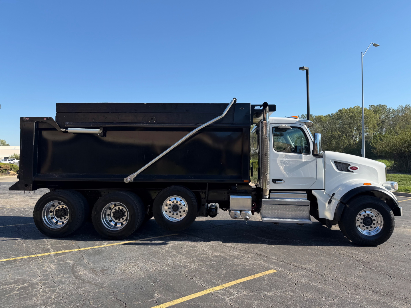Peterbilt 567 dump truck side view with black dump bed and gray cab