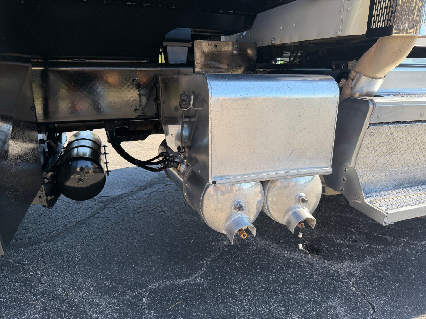 Dump truck undercarriage showing aluminum fuel tank, exhaust pipe, and underbody components.