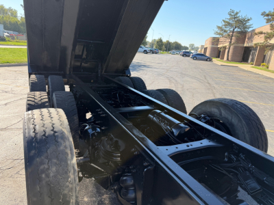 Truck chassis with dump bed raised showing rear axle and suspension; visible text includes VIN and stock number within the listing: 1NPCXPTX7PD870124 and 0633409.