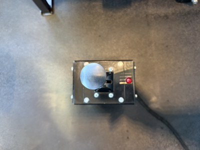 Dashboard area showing a round toggle knob and a small red indicator light on a black rectangular box with wiring attached.