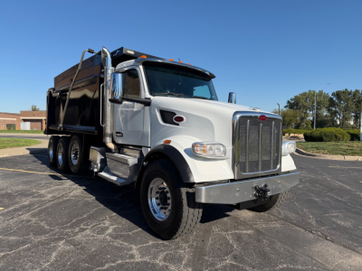 Peterbilt 567 dump truck in-service white cab with black dump body, front grille, headlights, and dual rear axles visible.