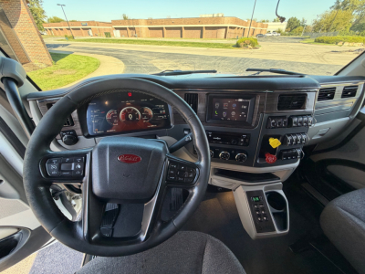 Peterbilt 567 truck interior showing steering wheel, instrument cluster, center console with touchscreen, gear selector, and control switches.